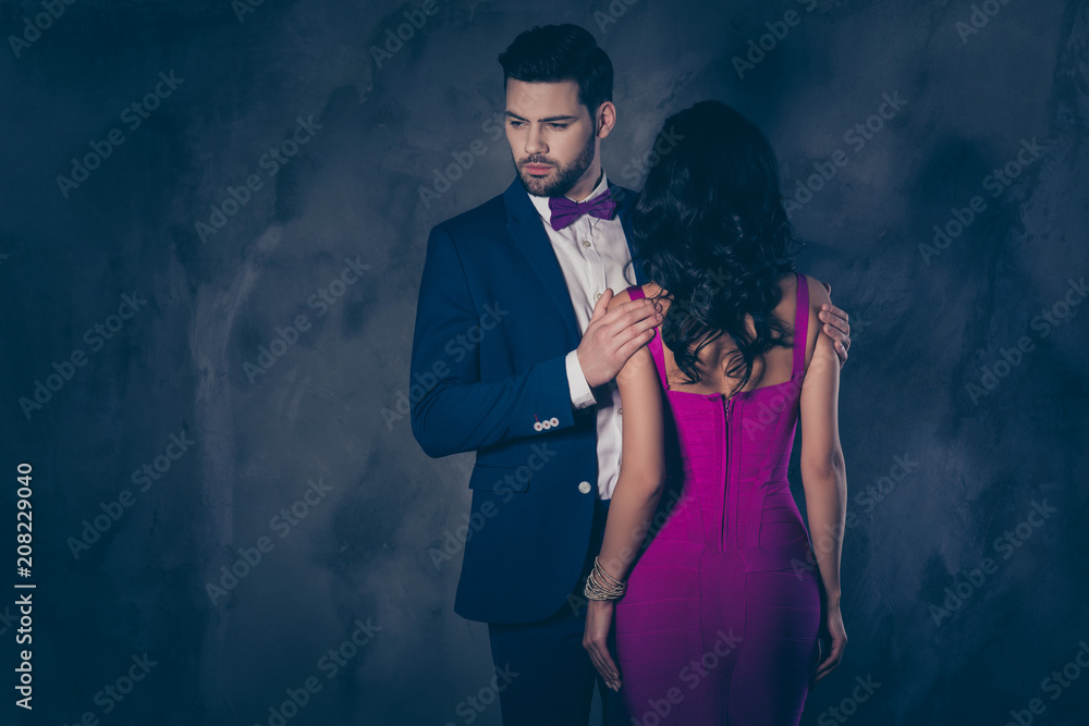 Poster rear view of pretty brunette woman with curly hair booty bum harsh man in tux with bow holding hands