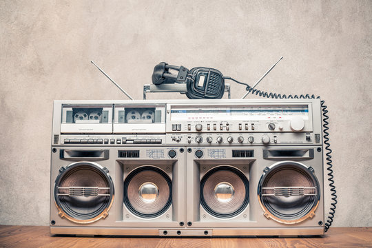 Retro old ghetto blaster stereo radio cassette tape recorder boombox from circa 1980s and headphones front concrete wall background. Vintage instagram style filtered photo