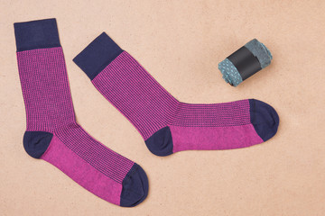 a pair of pink socks on a beige surface, next to one sock is twisted and packed, the concept