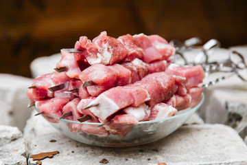 Marinated for shish kebab meat, sprinkled with black pepper and spices, lies in a plate on skewers