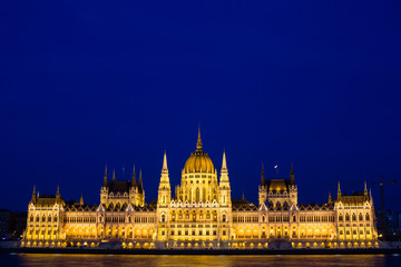 Fototapeta na wymiar Illuminated Budapest parliament building at night with dark sky and reflection in Danube river