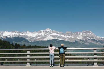 Fototapeta na wymiar back view of girls standing near fence and looking at majestic snow-capped mountains, mont blanc, alps
