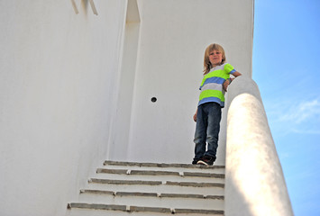 Little blond boy standing outside the house