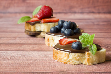Toast bread with chocolate paste and strawberries blueberries mint on the table Copy space