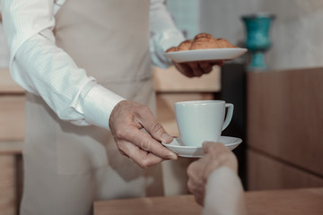 Favorite drink. Professional waiter stretching arms while supporting his client