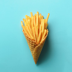 Fried potatoes in waffle cones on blue background. Hot salty french fries with tomato sauce. Fast food, junk food, diet concept. Top view. Minimal style. Pop art design, creative concept.