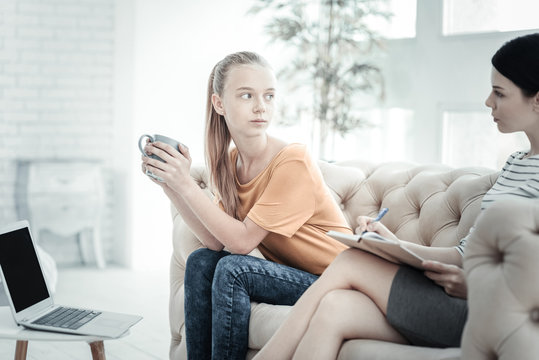 Therapeutic Moment. Female Ppsychologist Helping Innocent Calm Teen Girl While She Sitting And Drinking Tea