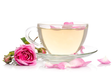 Glass cup of Tea with roses petals on light table