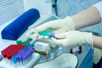 Preparation for urgent collection of blood samples from patient for analysis or research. A nurse or doctor in protective gloves opened sterile vacuum syringe with test tube samples for test sample
