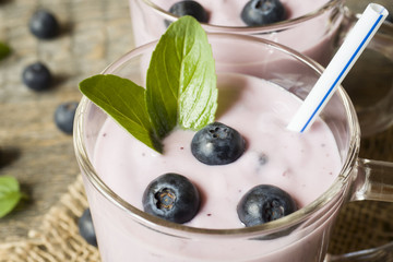 Blueberry yogurt in glass cups with fresh blueberries and mint on a wooden rustic table