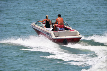 Young couple in a high end runabout motor boat speeding on the florida intra-coastal waterway off Miami Beach.