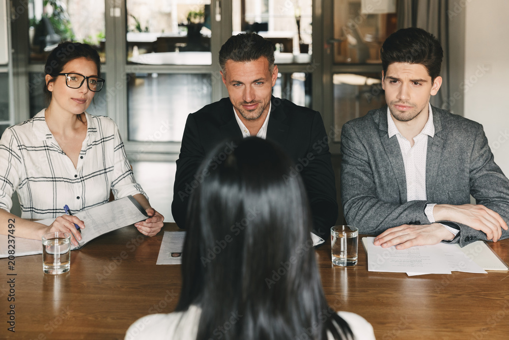 Poster Business, career and recruitment concept - group of employers in formal wear sitting at table in office, and interviewing woman for job in big corporation