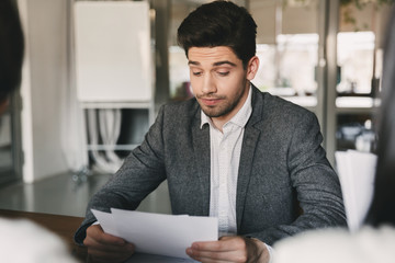 Business, career and placement concept - caucasian man 30s reading his resume or documents during...
