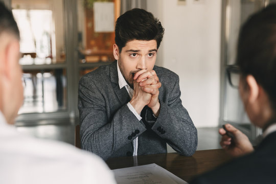Business, career and placement concept - caucasian uptight male applicant worrying and putting fists together during job interview in office, with board of directors