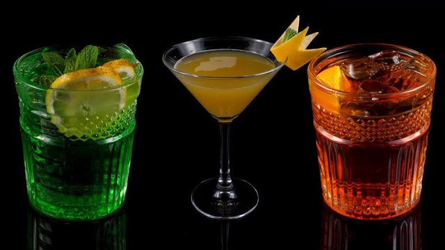 Cocktails on black, green, orange and red cold long drinks, background with reflections
