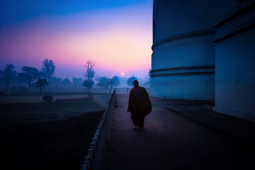 Sunrise and silhouette scene of Buddhist monk walking for meditation in the morning at Parinirvana Stupa, Mahaparinirvana Temple, Kushinagar, Uttar Pradesh, India. - obrazy, fototapety, plakaty