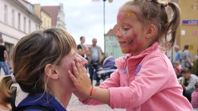 Mother and child daughter face paint body art after sprinkle colored powder festival
