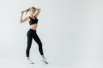 beautiful sportswoman in black sportswear standing isolated on grey