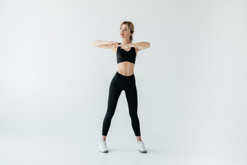 beautiful sportswoman in black sportswear standing isolated on grey