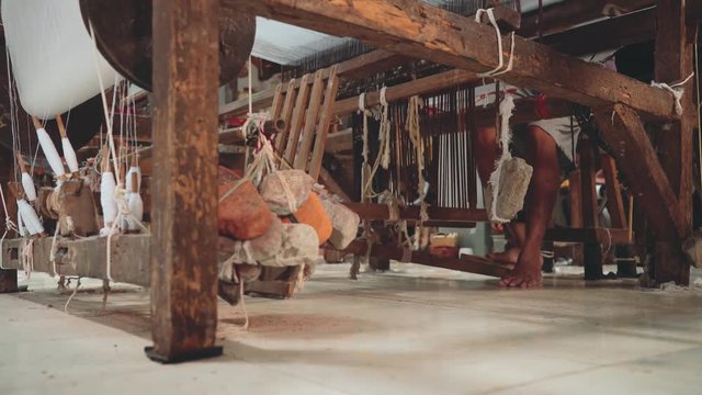 Indonesian man using foot-treadle loom machine with foot. Shot with Sony a7s and Atomos Ninja Flame in Indonesia