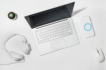Laptop 13.3 inches, white powerbank, white headphones, wireless mouse and cactus on a white...