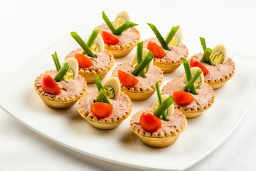 Three baguette slices with liver and apple pate and a thin tomato slice on top. Shallow DOF