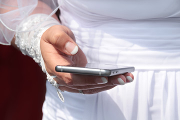 Frisch verheiratete Braut hält Mobiltelefon und versendet neueste Nachrichten