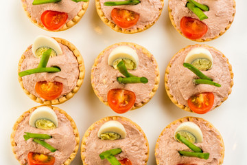 Three baguette slices with liver and apple pate and a thin tomato slice on top. Shallow DOF