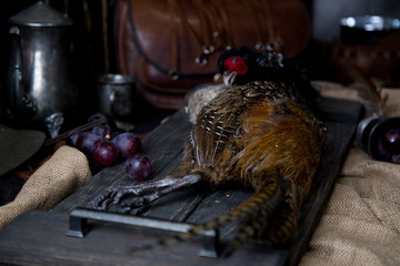Hunted pheasant on a wooden board with metal and leather details like holandese naturmorn