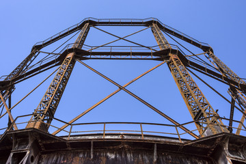 Detail of olf vintage historic rusty steel gas holder with blue sky in the background - concept...