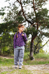 Little girl with backpack traveling in the forest