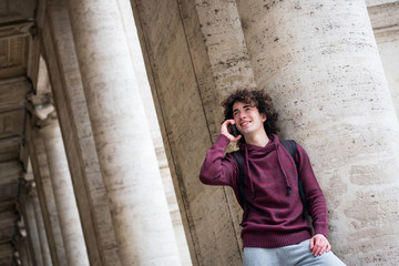 Handsome young man with curly hair in tracksuit talking on his mobile phone