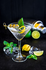 Cool transparent cocktail with olives on black background