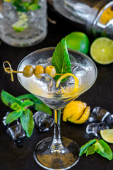 Cool transparent cocktail with olives on black background