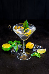 Cool transparent cocktail with olives on black background