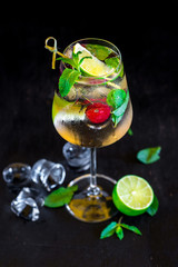 Fresh cold cocktail with lime and cherry on black background