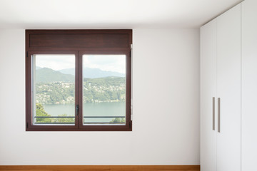 Fototapeta na wymiar White empty room with windows overlooking the lake and large white wardrobe