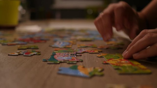 Single woman at home play folds puzzle at the kitchen table not to be bored