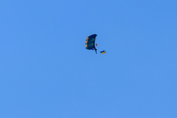Parachutist carrying flag of Ukraine in blue clear sky