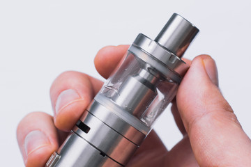 Vape concept, toned Vape Man hand shows vape device at cloud of vapor background.