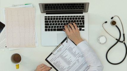 Female doctor filling in form and making consultation by skype