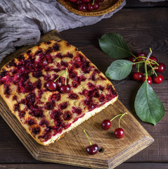 baked cake with cherries on a brown wooden board