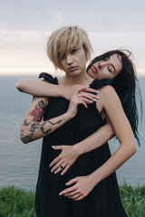 beautiful young women embracing in front of ocean on cloudy day