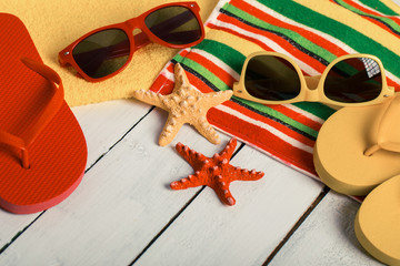 Flip flops, ball, tablet pc, seashell and starfish with tropical flowers on sandy beach