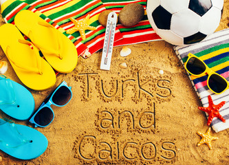Summer concept of sandy beach, colorful flip flop shoes, sunglasses, ball and inscription turks and...