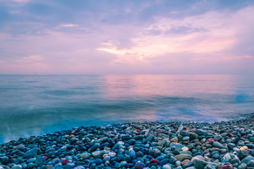 Pink Sunset over the sea and a rocky beach