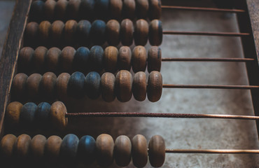 Old wooden abacus laying on the dusty floor of the storage. Closeup