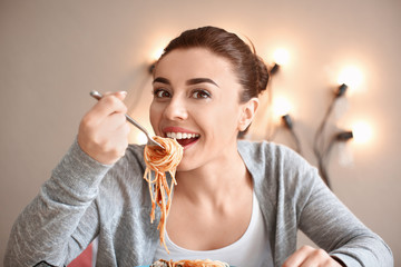 Young woman eating tasty pasta in cafe