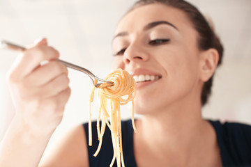 Fototapeta premium Young woman eating tasty pasta in restaurant