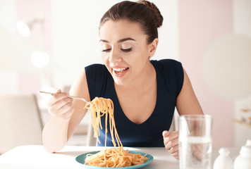 Young woman eating tasty pasta in cafe